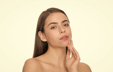 Genç bir kadın yumuşak bir yüze dokunur beyaz arka planda soyutlanmış ten, güzellik