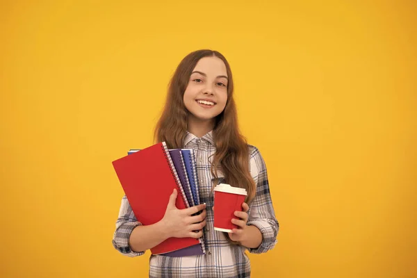 Wesoły nastolatek dziewczyna w kratkę koszula trzyma filiżankę kawy i notatnik, dzieciństwo. — Zdjęcie stockowe