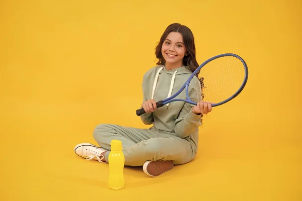 Kinder sitzen mit Schläger und Wasserflasche. Kind mit Tennisschläger. teen girl nach sport training. — Stockfoto