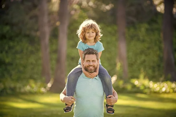 Feliz padre hombre llevar niño niño sentado en padres hombros verano al aire libre, piggy-back — Foto de Stock