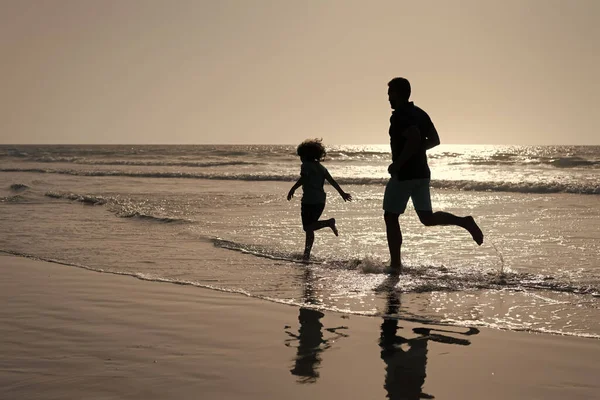 Ojciec i syn sylwetki działa zabawy i poczuć wolność na letniej plaży, letnie wakacje — Zdjęcie stockowe