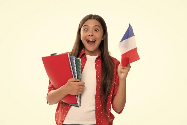 Meghökkent gyerek tart francia zászló és iskolai copybook a tanulás elszigetelt fehér, külföldön tanulni — Stock Fotó
