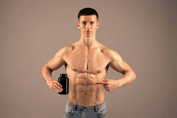 Suplementy warte wzięcia. Człowiek bez koszuli wskazuje palcem na proteinową butelkę. Suplementy diety — Zdjęcie stockowe