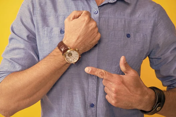 Przycięty człowiek wskazując palcem na dłoni zegarek na żółtym tle, czas — Zdjęcie stockowe