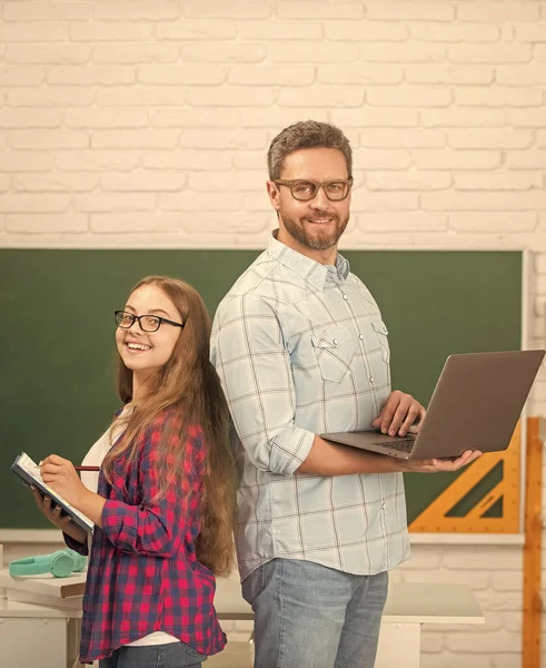 Щаслива дитина і тато в класі з книгою і комп'ютером на дошці, онлайн-урок — стокове фото