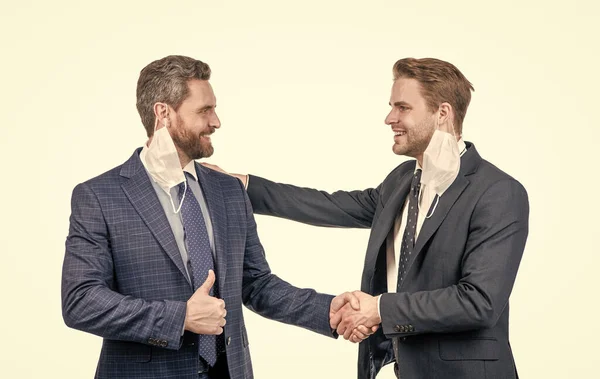 Двое мужчин в маске пожимают друг другу руки. бизнесмены на встрече. Health concept. — стоковое фото