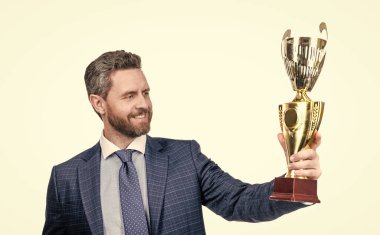 Resmi giyim dalında gururlu menajer iş başarısı için altın kupayı beyaz ve gururlu bir şekilde sakladı.