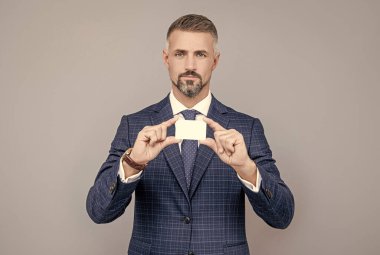 İş adamı kılığındaki kendine güvenen iş adamı fotokopi alanı ve iş yeri için kartvizit gösteriyor.