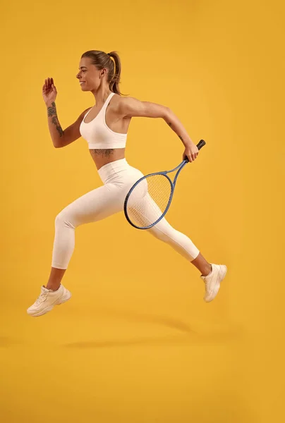 Glad tennisspelare kör med racket på gul bakgrund, badminton — Stockfoto