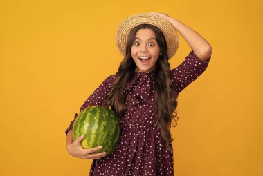 Yazın hasır şapkalı taze su kavunu meyvesi tutan hayret verici çocuk. Beslenme.