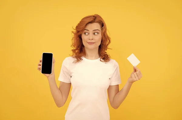 Mujer sorprendida mostrando tarjeta de crédito o débito y teléfono inteligente para hacer compras en línea, negocio en línea. —  Fotos de Stock