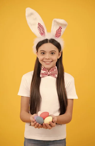 Szczęśliwy Wielkanoc nastolatek dziewczyna w królicze uszy i muszka trzymać malowane jaja, Pisanka — Zdjęcie stockowe