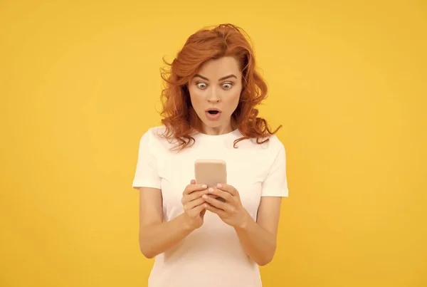Femeia surprinsă cu smartphone-ul pe fundal galben — Fotografie, imagine de stoc