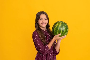Sarı arka planda taze olgun karpuz meyvesi tutan mutlu çocuk, yaz mevsimi.