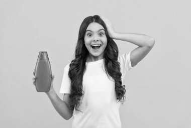 Uzun saçlı, şaşkın çocuk. Şampuan şişesi, saç.