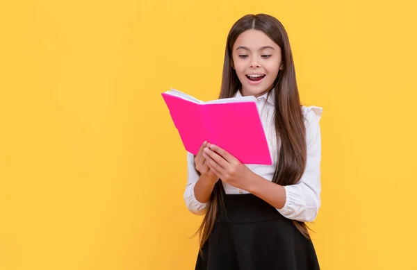 Щаслива дівчинка читає шкільний підручник жовтий фон, читання — стокове фото