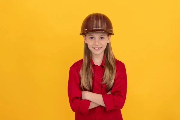 Positivo teen bambino in casco costruttore su sfondo giallo — Foto Stock