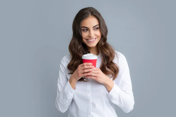 Hermosa mujer en el estudio sosteniendo una taza de café. Foto de alegre chica positiva bonita sosteniendo taza de café sonriendo toothily aislado sobre fondo gris. — Foto de Stock
