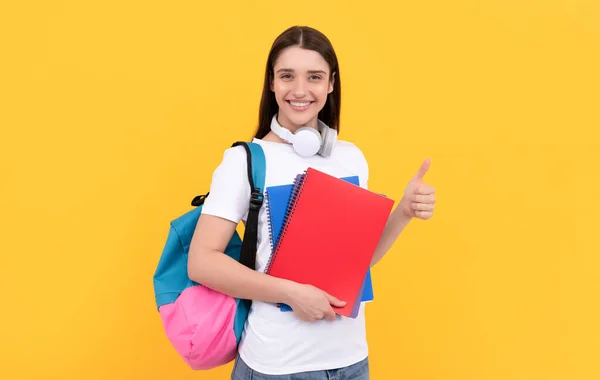 happy girl holding notebook on yellow background. private teacher with copybooks