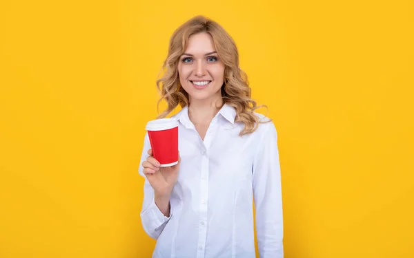Cheerful blonde woman with coffee cup on yellow background — Stockfoto