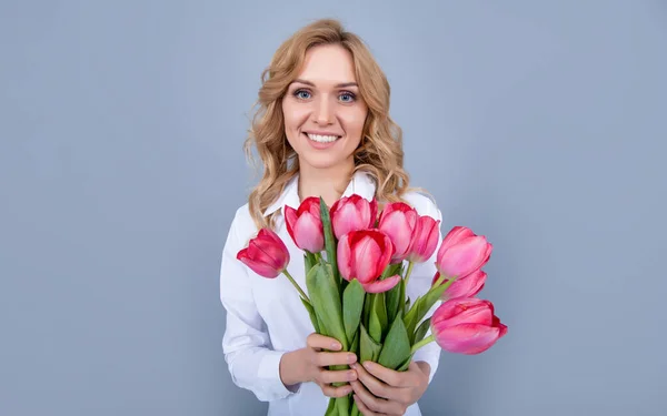 Gri arka planda bahar lale çiçekleri tutan mutlu genç kadın. — Stok fotoğraf