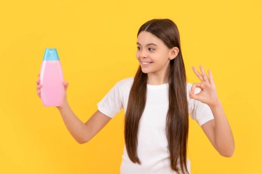 Mutlu çocuk şampuan şişesi göster Sarı arka planda jest, cilt bakımı