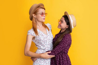 Sarı arka planda hasır şapkalı neşeli anne ve çocuk