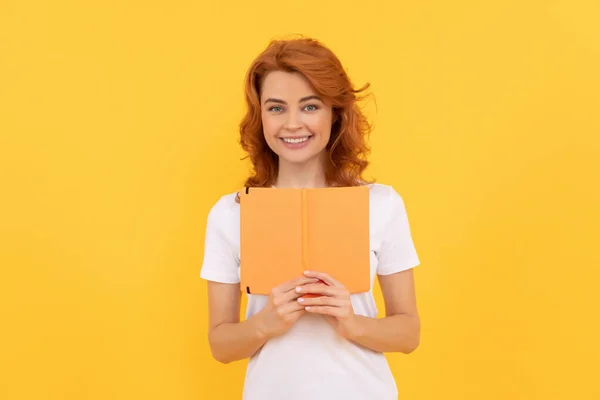 Positive girl hold copybook on yellow background, reader — Stok fotoğraf