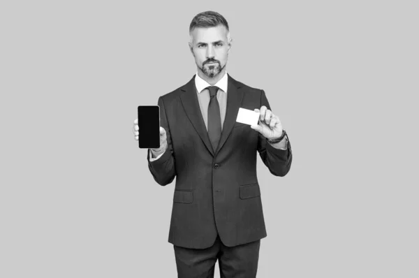 Dojrzałe mężczyzna doradca pokazując karty kredytowe lub debetowe i smartphone kopiowanie miejsca, bankowość online. — Zdjęcie stockowe