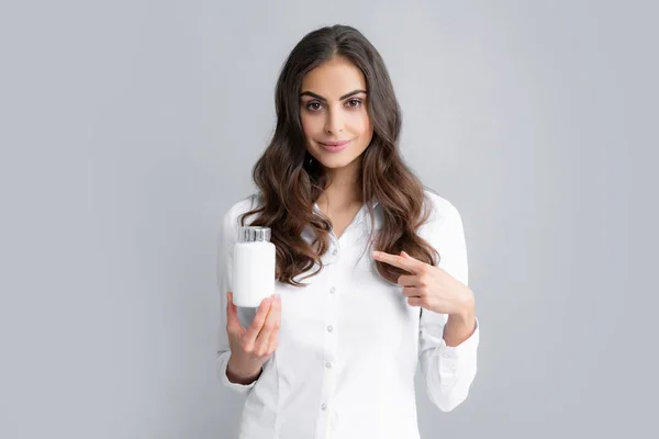 Healthcare and medicine. Portrait of attractive girl holding on bottle pills healthy product over gray background.
