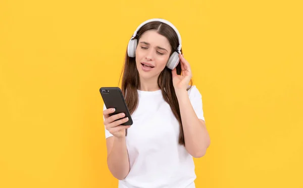 Dame en chemise blanche chantant dans les écouteurs et bavardant sur le téléphone, la technologie — Photo