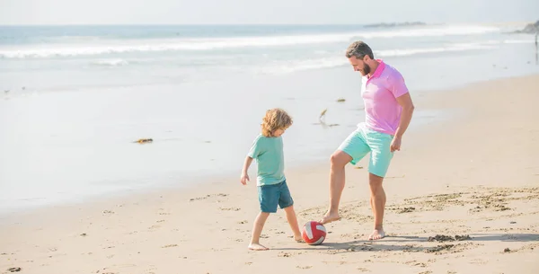 Cheerful father and son play football on summer beach with ball, parenting — Fotografia de Stock