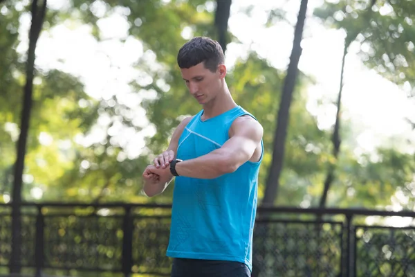 Man runner in activewear checking time on smartwatch — 스톡 사진