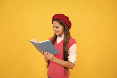 Fransız bereli mutlu genç kız sarı arka plan üzerine kitap okuyor, okuyucu.