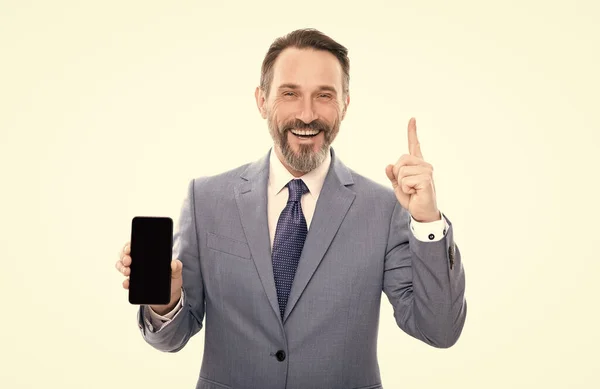 Happy grizzled entrepreneur presenting modern smartphone isolated on white copy space, advise. — Stockfoto