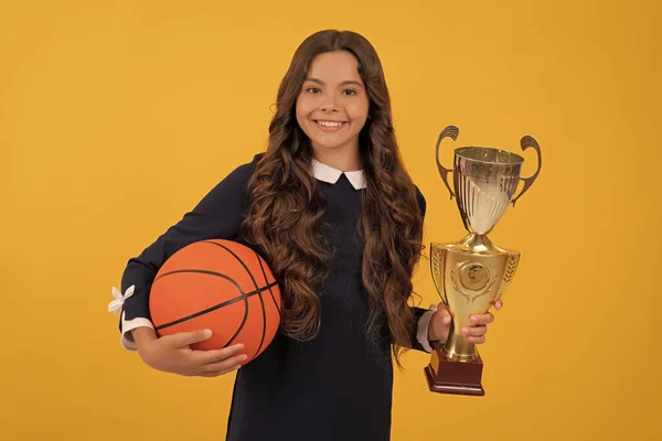 즐거운 아이가 농구 공 과 챔피언 컵을 노란 배경에서 개최, 승리 — 스톡 사진