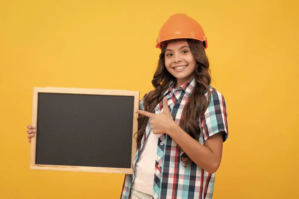 Gülümseyen genç işçi kız kara tahtayı işaret ediyor. Çocuk reklamları günü. — Stok fotoğraf