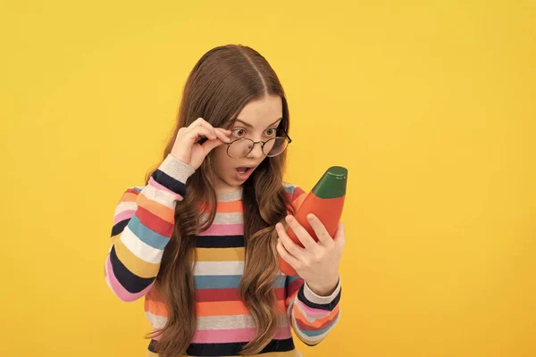 Erstaunt teen girl lange haare in brille mit blick auf shampoo-flasche, haircare — Stockfoto