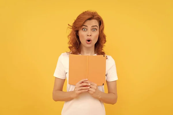 Női olvasó. megdöbbent diák sárga háttérrel. lány tanulmány könyv. — Stock Fotó