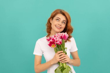 Mavi arka planda lale çiçeği buketi olan mutlu hayalperest kız.