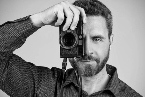 Orta yaşlı fotoğrafçı, fotoğraf makinesinin gözünün içine bakarak fotoğraf çeker..