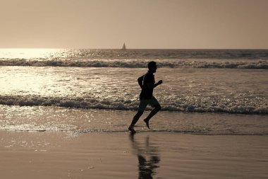 Sahilde koşan sağlıklı bir adam. Enerjik bir yaz. Koşucu özgürlüğü hisseder. Acele et..