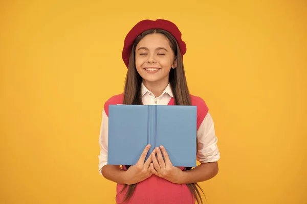 Мечтательная девочка-подросток в французском берете чтение книги на желтом фоне, представьте — стоковое фото