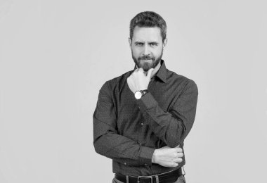 Orta yaşlı, tıraşsız, ciddi görünüşlü, sakallı, sıradan moda tarzında sakallı bir adam..