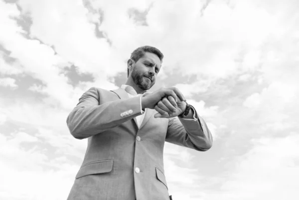 Guapo hombre maduro hombre de negocios en traje formal comprobar el tiempo en el reloj de pulsera en el fondo del cielo, plazo — Foto de Stock