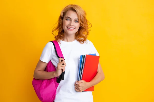 Ενθουσιασμένη κοκκινομάλλα νεαρή φοιτήτρια με σημειωματάρια σακίδιο, απομονωμένη σε κίτρινο φόντο στούντιο Εκπαίδευση στο γυμνάσιο πανεπιστήμιο. — Φωτογραφία Αρχείου