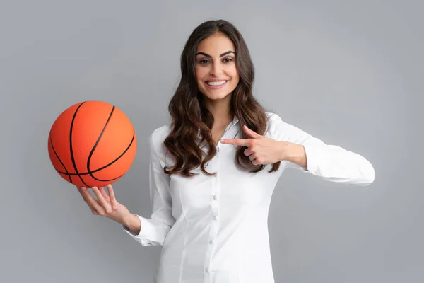 Щаслива жінка вказує пальцем на баскетбол, ізольована на сірому фоні . — стокове фото