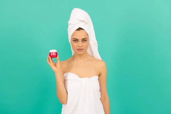 Young woman in towel with skin cream on blue background — Stock Photo, Image