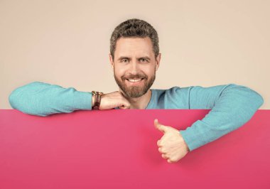 Yenilik bilgisi sunuyorum. Pembe kağıdın arkasındaki erkek baş parmağını gösteriyor..