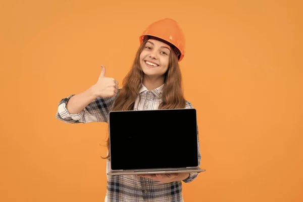 Kasklı, kareli tişörtlü bilgisayar sunan mutlu genç kız, başparmağını kaldır. — Stok fotoğraf